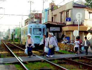 写真１５－１：安立町駅で踏切を渡る人を待つ阪堺電車。